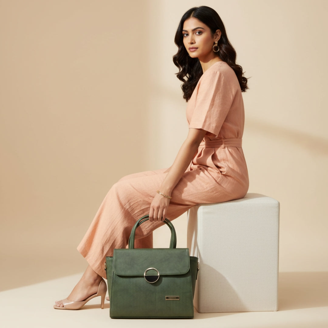 Woman in a peach outfit holding a green handbag against a beige background